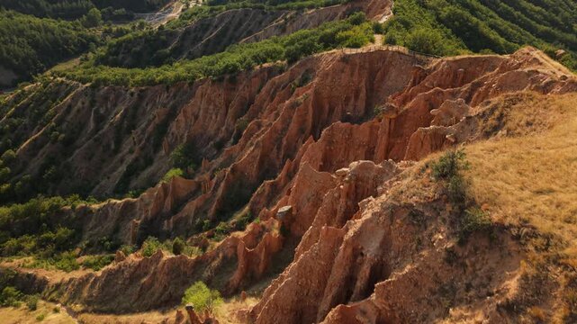 Cinematic aerial of the Stob Pyramids Bulgaria sandstone formations framed by hills forests and valleys.