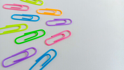 Colorful paperclips in assorted neon shades arranged on a white background, representing stationery tools for office, school, and organization. With copy space