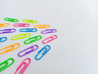 Colorful paperclips in assorted neon shades arranged on a white background, representing stationery tools for office, school, and organization. With copy space