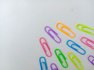 Colorful paperclips in assorted neon shades arranged on a white background, representing stationery tools for office, school, and organization. With copy space