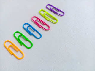 Colorful paperclips in assorted neon shades arranged on a white background, representing stationery tools for office, school, and organization. With copy space