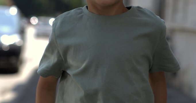 Close up of young boy&rsquo;s torso as he jumps upward on urban street, captured in super slow motion with high-speed camera during daylight