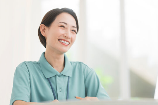 ポロシャツを着用しネームプレートを首から下げてカウンセリングをしている女性。