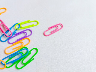 Colorful paperclips in assorted neon shades arranged on a white background, representing stationery tools for office, school, and organization. With copy space