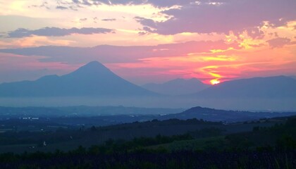 Vibrant sunset over hazy mountains and rolling hills