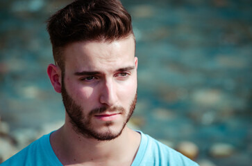 Young man with short hair by the water during a sunny day