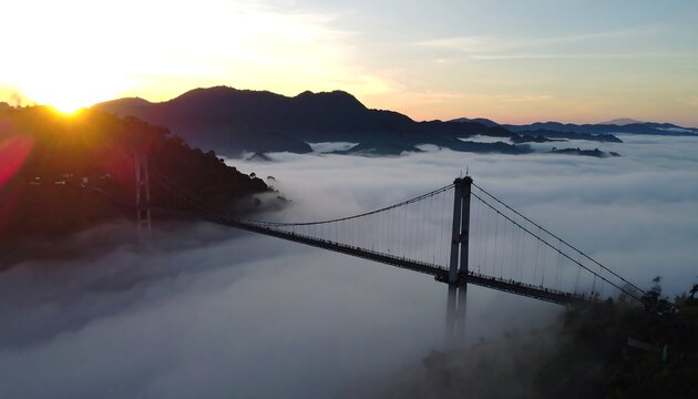 Sunrise over a suspension bridge nestled in a misty mountain valley