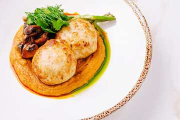 Gourmet chicken patties served with vegetable puree, roasted mushrooms, fresh herbs and grilled asparagus on ceramic plate.