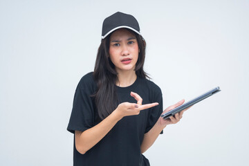A displeased young Asian woman captured in a half body view holding a tablet and pointing at it...
