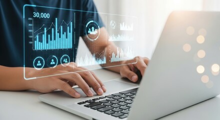 A person analyzes financial data on a laptop with a glowing holographic interface displaying charts and graphs