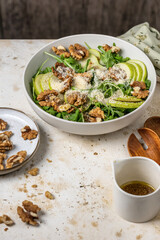 Salad with Pear, Arugula, cheese and walnuts. Delicious Fresh Salad on light textured background