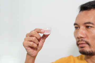 A man carefully uses eye drops or an eye wash solution, focusing on his eye health and personal hygiene routine to maintain clear and comfortable vision.