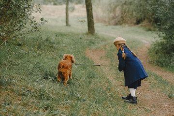 Little girl walks in autumn forest with a dog