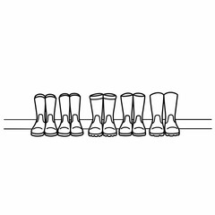 Line of rubber boots arranged neatly on a shelf against a white background  