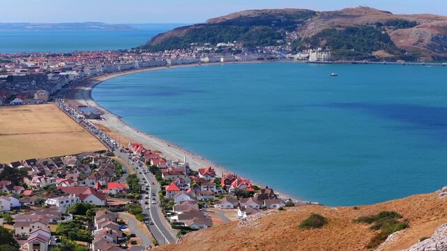 Aerial video of Llandudno Bay with the sweeping coastline, clear blue sea from the hills of Little Orme. 