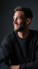 Fototapeta premium Smiling young man looking up with hope and positivity on dark background