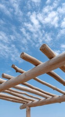 Obraz premium Wooden beams create a rustic structure against a blue sky with scattered clouds in a serene outdoor setting