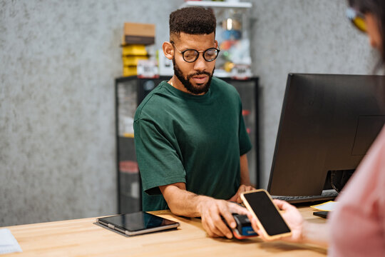 Bicycle shop worker accepting payment via NFC from customer's smartphone