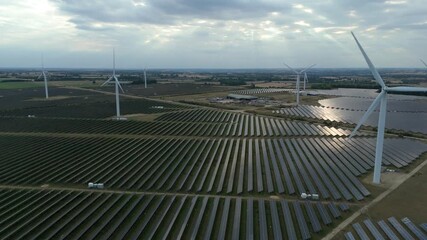 Aerial drone footage of huge solar power photovoltaic and wind turbine energy plant, generating renewable green electricity near Northampton England UK - Powered by Adobe