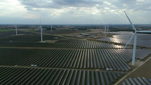 Aerial drone footage of huge solar power photovoltaic and wind turbine energy plant, generating renewable green electricity near Northampton England UK - Powered by Adobe