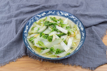 The stir-fried cabbage with vegetables on the white plate at the dining table