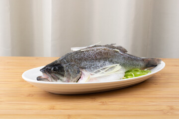 Fresh steamed sea bass ingredients in a porcelain plate