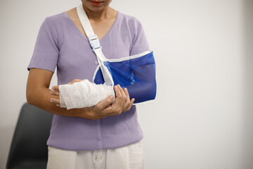 A person from the chest up wears a light green cardigan over a white shirt, with their right...