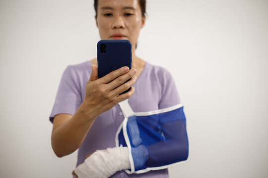 A person from the chest up wears a light green cardigan over a white shirt, with their right forearm wrapped in a beige bandage and supported inside a blue mesh arm sling. - Powered by Adobe