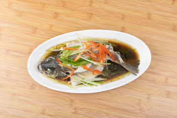 Steamed sea bass in a white porcelain plate
