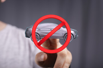 Image of a hand holding a no car sign, representing driving restrictions or prohibitions.