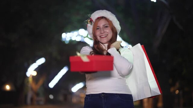 Woman opening glowing Christmas gift box at night with festive lights background