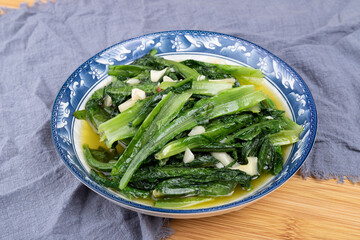 The vegetarian stir-fried romaine lettuce on a white plate of Sichuan cuisine
