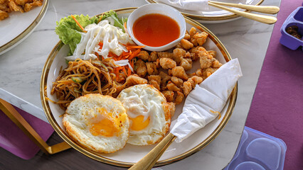 crispy chicken, fried eggs, noodles, fresh salad and sauce