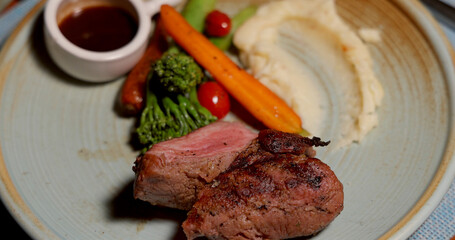 Grilled steak with mashed potatoes, roasted vegetables, and sauce on rustic plate. Elegant dining experience, gourmet cuisine, meat meal, culinary delight.