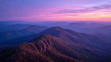 Fototapeta premium mountain ridge shrouded in mist at sunrise beneath purple sky 