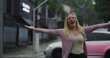 Woman celebrating in rain with arms outstretched, radiant smile, and joyful expression in moment of emotional freedom and pure happiness