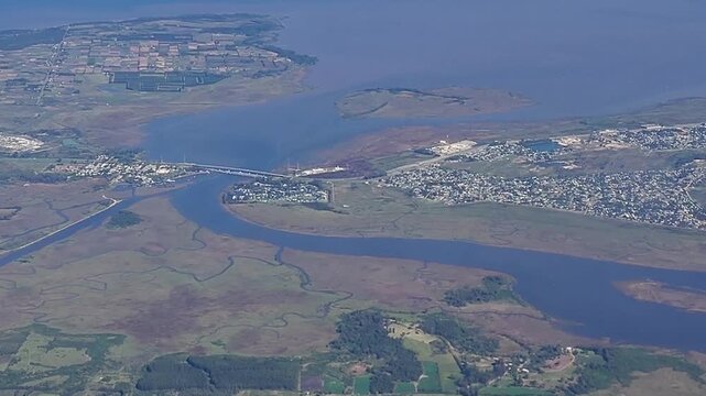 Sweeping aerial landscape video of coastal and small towns at canelones department, captured from the passenger window of an airplane. 