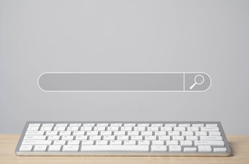 A wireless keyboard on a desk with a digital search bar floating above, symbolizing online search and internet browsing.