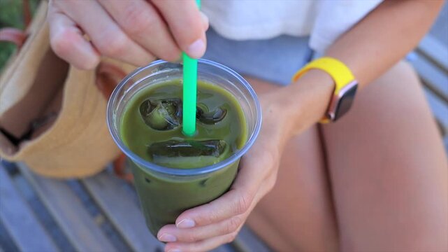 Refreshing iced green matcha tea in a plastic cup with a straw