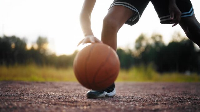 Dribbling and bouncing ball in basketball, closeup view of streetballer workout . Sports activity for teenagers and children, professional sport and hobby, comfortable footwear for sportsmen, details