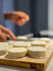 Woman preparing biscuits and arranging cottage cheese dough circles on a wooden board