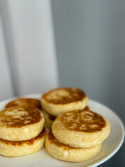 Golden cottage cheese pancakes syrniki 
stacked on a white plate