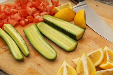 Sliced Cucumber, Lemons, and Tomatoes on Wooden Cutting Board