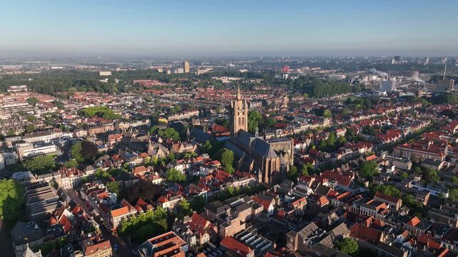 Drone pan right showing the skyline of Delft with Nieuwe Kerk tower under bright summer daylight.
