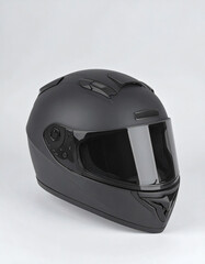 A matte black full-face motorcycle helmet with a tinted visor is displayed against a plain white background.
