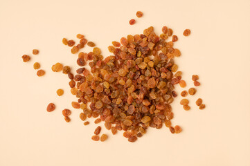 Dried golden brown raisins scattered on beige background flat lay top view. Grapes berries, sweet healthy snack, organic dried fruits. Food background, space for text
