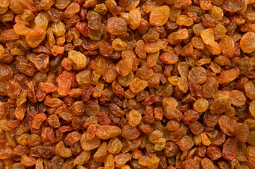 Dried brown golden raisins close-up top view. Texture of scattered organic raisins, macro photography. Sweet tasty dried fruit, dried grapes. Ingredient for cooking, baking desserts