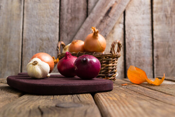 onions and garlics on cutting board, weathered wooden background