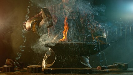 The blacksmith manually forging the molten metal on the anvil in smithy with spark fireworks