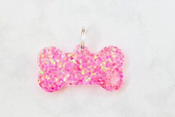 Pink Glitter Resin Dog Bone Tag with Paw Print on White Marble Background